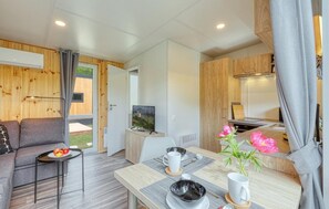 Une pièce moderne et bien éclairée, comprenant un canapé, une table à manger et un coin cuisine.