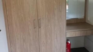 A room with a wooden wardrobe, a small shelf, and a red fire extinguisher. - Apartment 'Wemding' with Shared Terrace, Private Garden and Air Conditioning (Wemding)