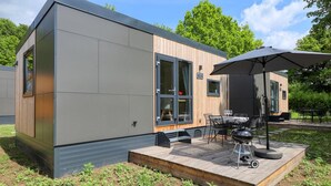 A modern, compact house with a deck, outdoor seating, and a barbecue. - Apartment 'Wemding' with Shared Terrace, Private Garden and Air Conditioning (Wemding)