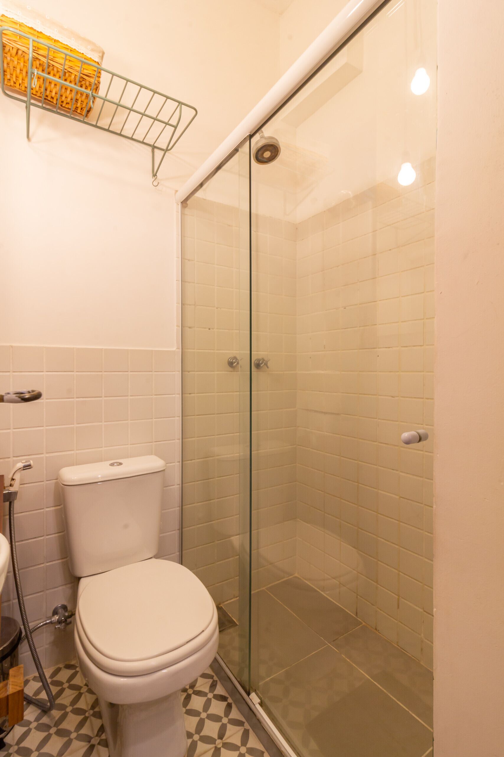 Une salle de bain comprenant des toilettes, une douche avec une porte en verre et un sol carrelé.
