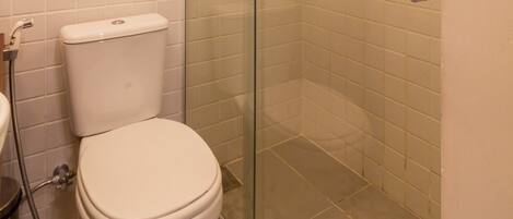 Une salle de bain comprenant des toilettes, une douche avec une porte en verre et un sol carrelé.