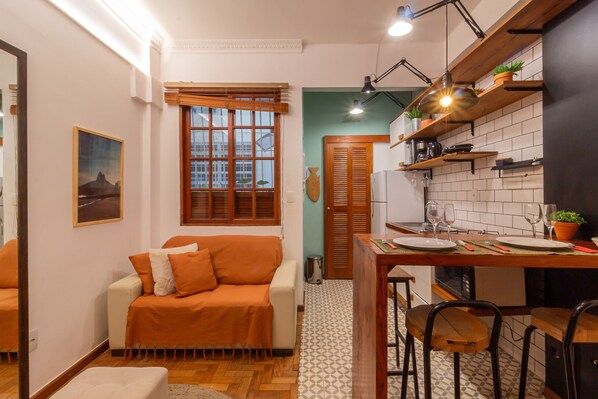 A compact living space with a kitchenette, a dining area, and a sofa.