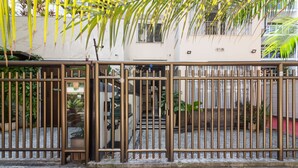 A gated entrance with a metal fence, a paved pathway, and a small garden area with potted plants.