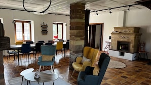 Un vaste espace de vie comprenant un coin salon avec cheminée, un coin repas et une grande fenêtre.