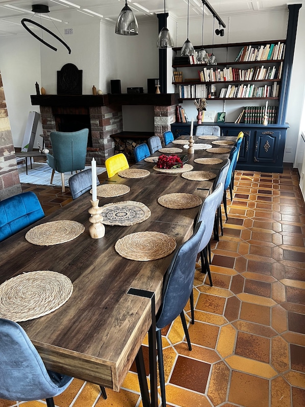 A dining area with a long wooden table, woven placemats, and modern chairs.