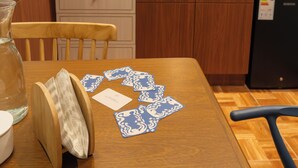 Een keuken met houten kastjes, een betegelde spatwand en een eettafel met speelkaarten.