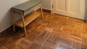 Een kamer met een houten bank, een deur met een groene gordijntje en een raam.