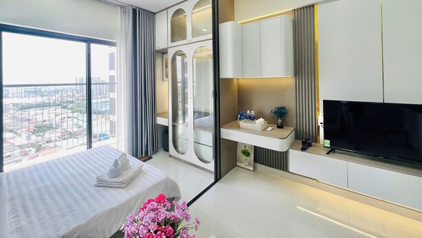 A modern hotel room with a large bed, a TV, and a view of the city. - New Lavida (Ho Chi Minh City)