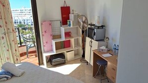A bedroom with a bed, a desk, a chair, a TV, and a balcony with a view of buildings. - Room + bathroom, splendid sea view, well equipped (Callao Salvaje)