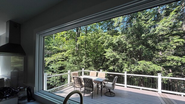 Une cuisine dotée d’une grande fenêtre donnant sur une terrasse aménagée avec du mobilier d’extérieur.