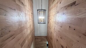 Un escalier en bois surmonté d’un luminaire suspendu.