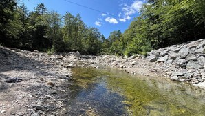 Un ruisseau aux eaux claires, bordé de rochers et d’arbres.