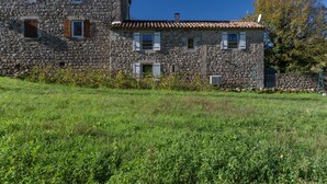 A stone building with multiple windows and a red-tiled roof. - Cottage 'L'Ancienne Estable' with Private Terrace, Private Garden and Air Conditioning (Les Assions)