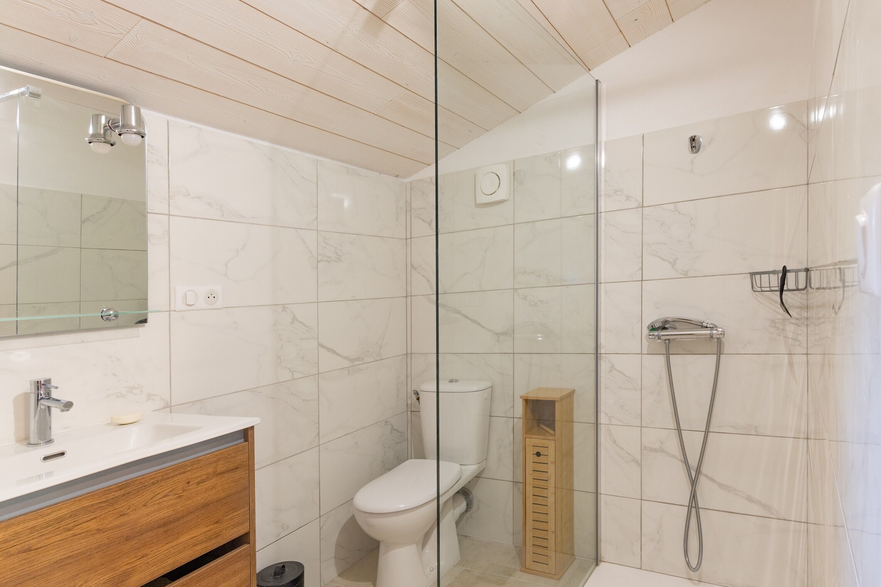 Een moderne badkamer met een douchecabine van glas, een toilet en een wastafel met spiegel.