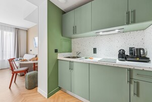 Una cocina moderna con gabinetes verdes, una encimera blanca y una cafetera.