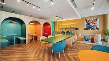 A modern interior with a long table, multiple chairs, and a seating area with sofas.
