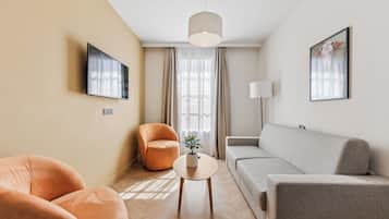Een moderne woonkamer met een bank, fauteuil en een kleine tafel met een plant.