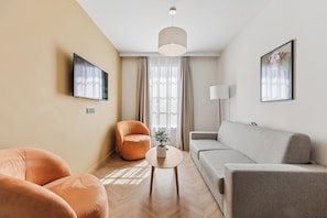 A modern living room with a sofa, armchair, and a small table with a plant. - All Suites Appart Hôtel | Val d’Europe près de Disneyland® Paris (Serris)