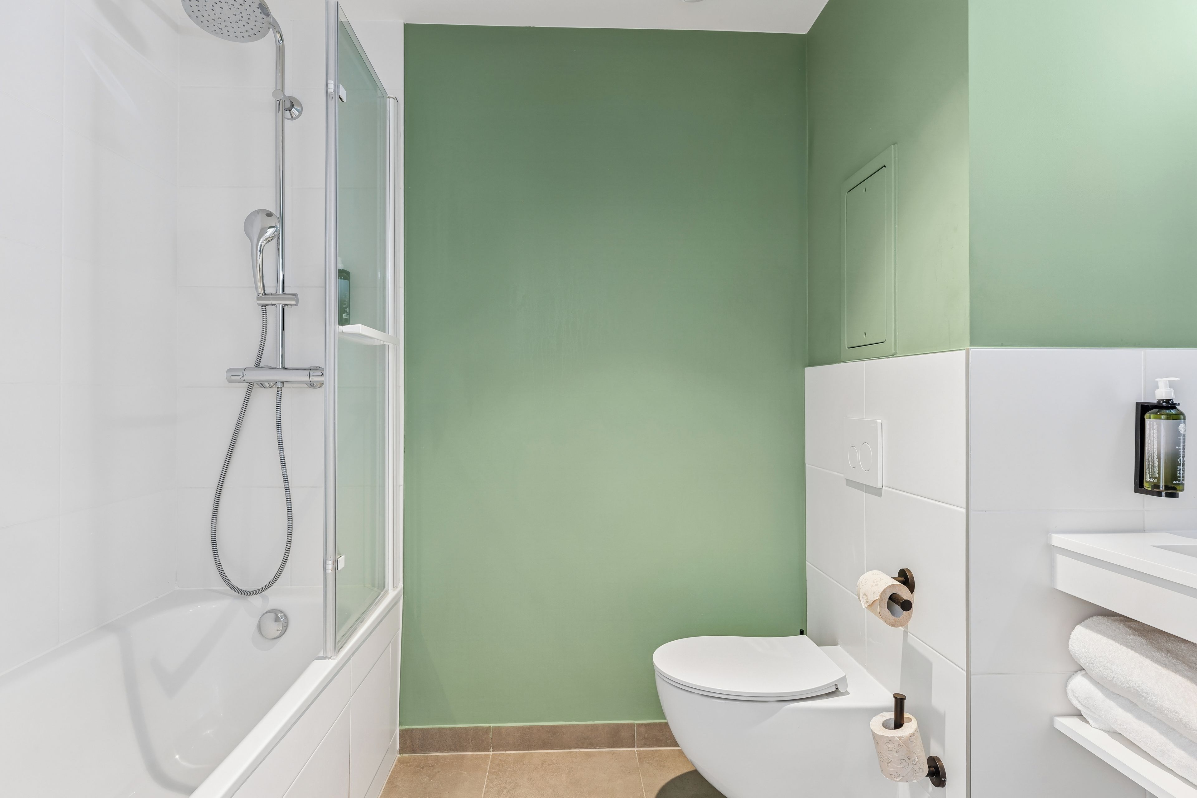 Un baño con ducha, inodoro y un perchero para toallas.