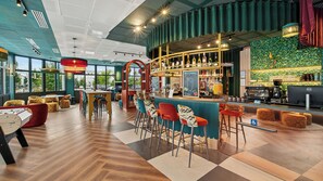 A modern bar area with a bar counter, stools, and a variety of bottles. - All Suites Appart Hôtel | Val d’Europe près de Disneyland® Paris (Serris)