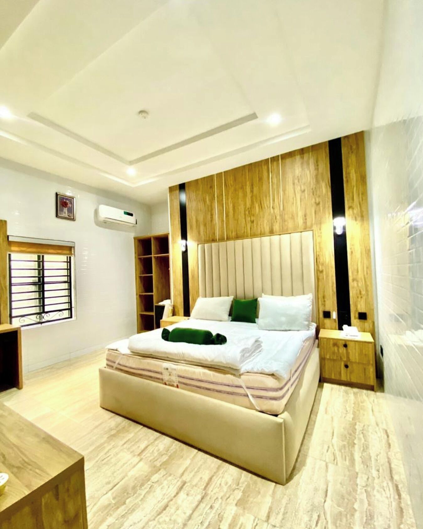A modern bedroom with a large bed, wooden headboard, bedside tables, and a built-in wardrobe.