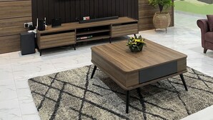 Ein modernes Wohnzimmer mit einem großen Flachbildfernseher an einer Wand aus Holzpaneelen, einem Couchtisch und einer Topfpflanze.