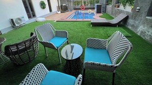 Eine moderne Außenpatio mit Korbmöbeln, einem Pool und Blick auf ein Gebäude im Hintergrund.
