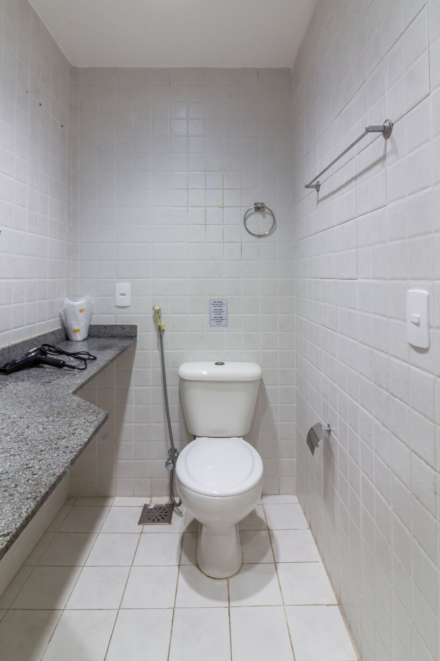 Une petite salle de bain propre, équipée de toilettes, d’un lavabo et d’une douche.