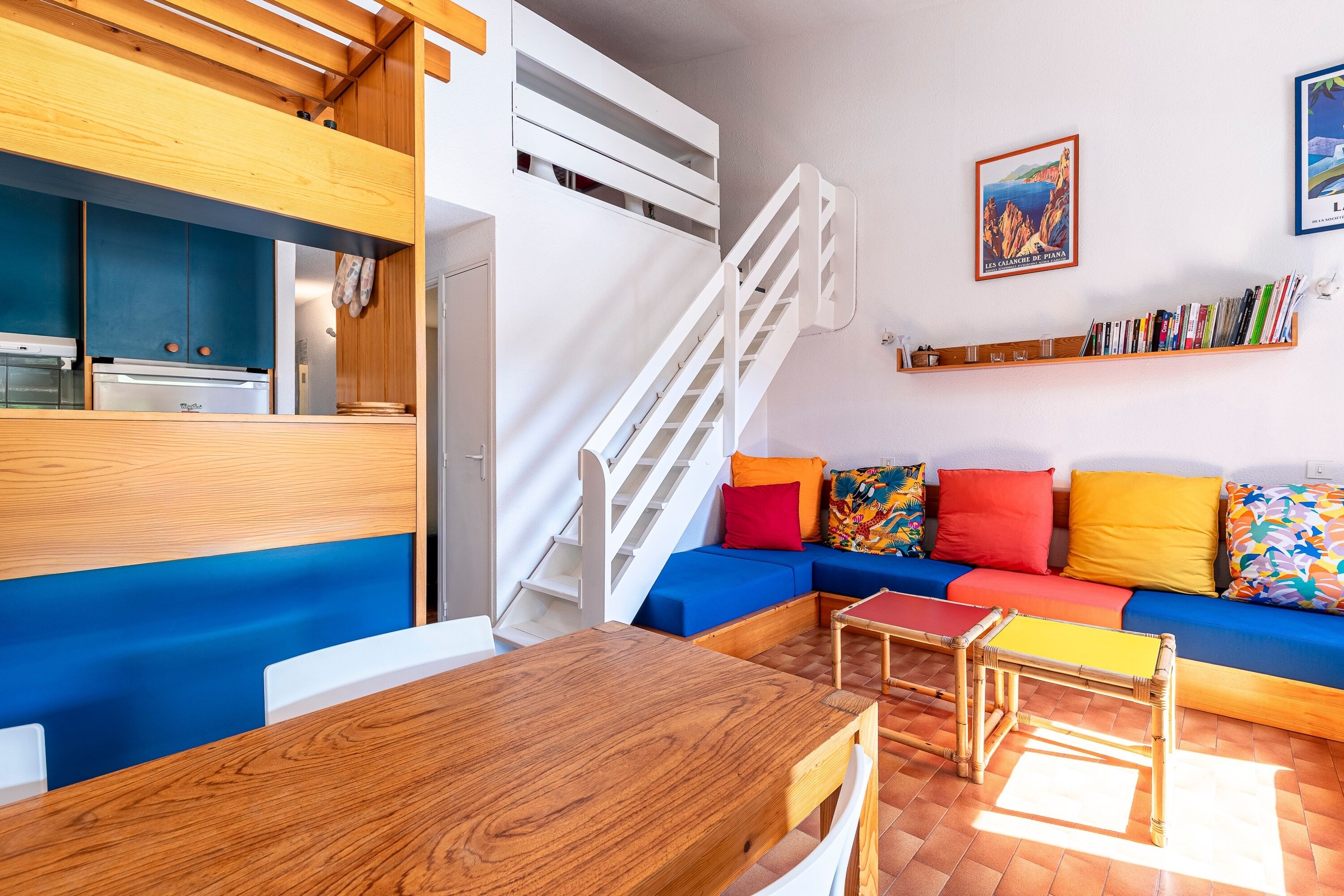 A modern living space with a kitchen, a dining area, and a colorful sofa set.
