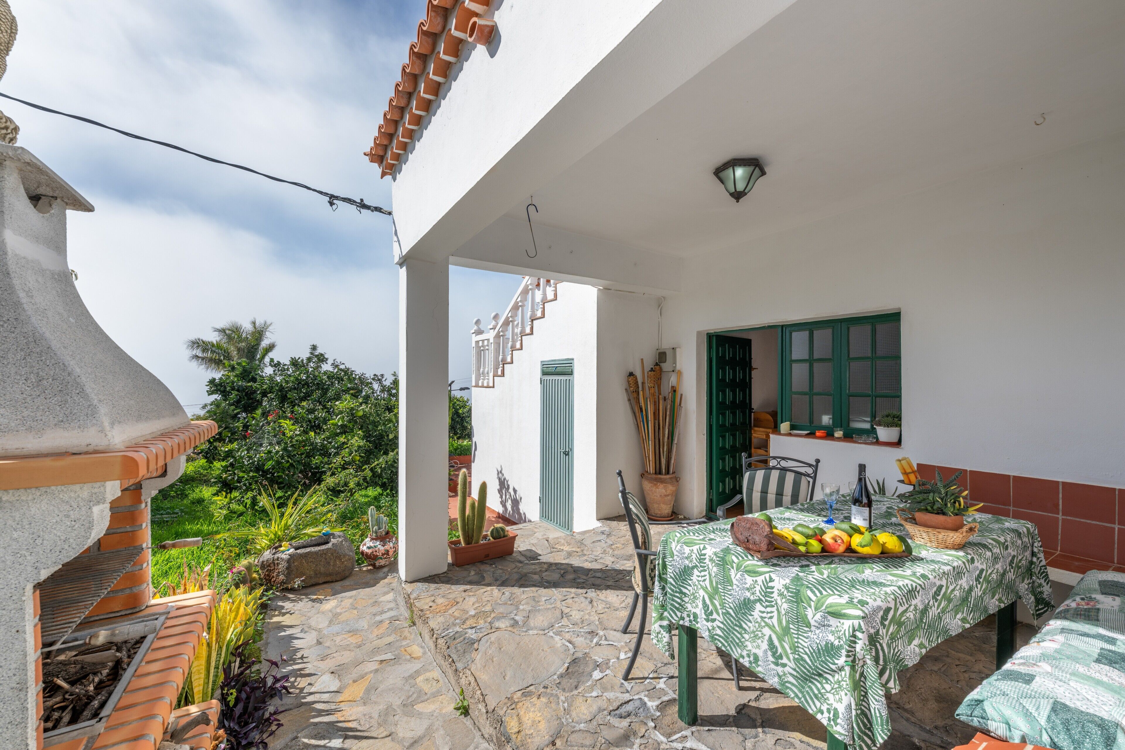 Eine Terrassenfläche mit Esstisch, umgeben von Topfpflanzen und einem Steinboden.