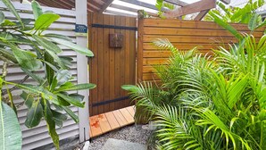 A wooden gate with a sign, surrounded by lush greenery and a wooden deck. - Lodge 2 - Hibiscus - Jaccuzi Privé (Les Anses-d'Arlet)