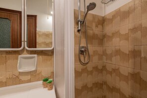 Une salle de bain avec une douche, un miroir et un petit lavabo.