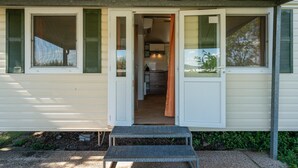 A single-story house with a covered porch, a small outdoor seating area, and a visible kitchen area.