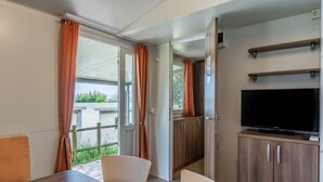 A room with a dining table, chairs, a TV on a cabinet, and a sliding door to the outside.
