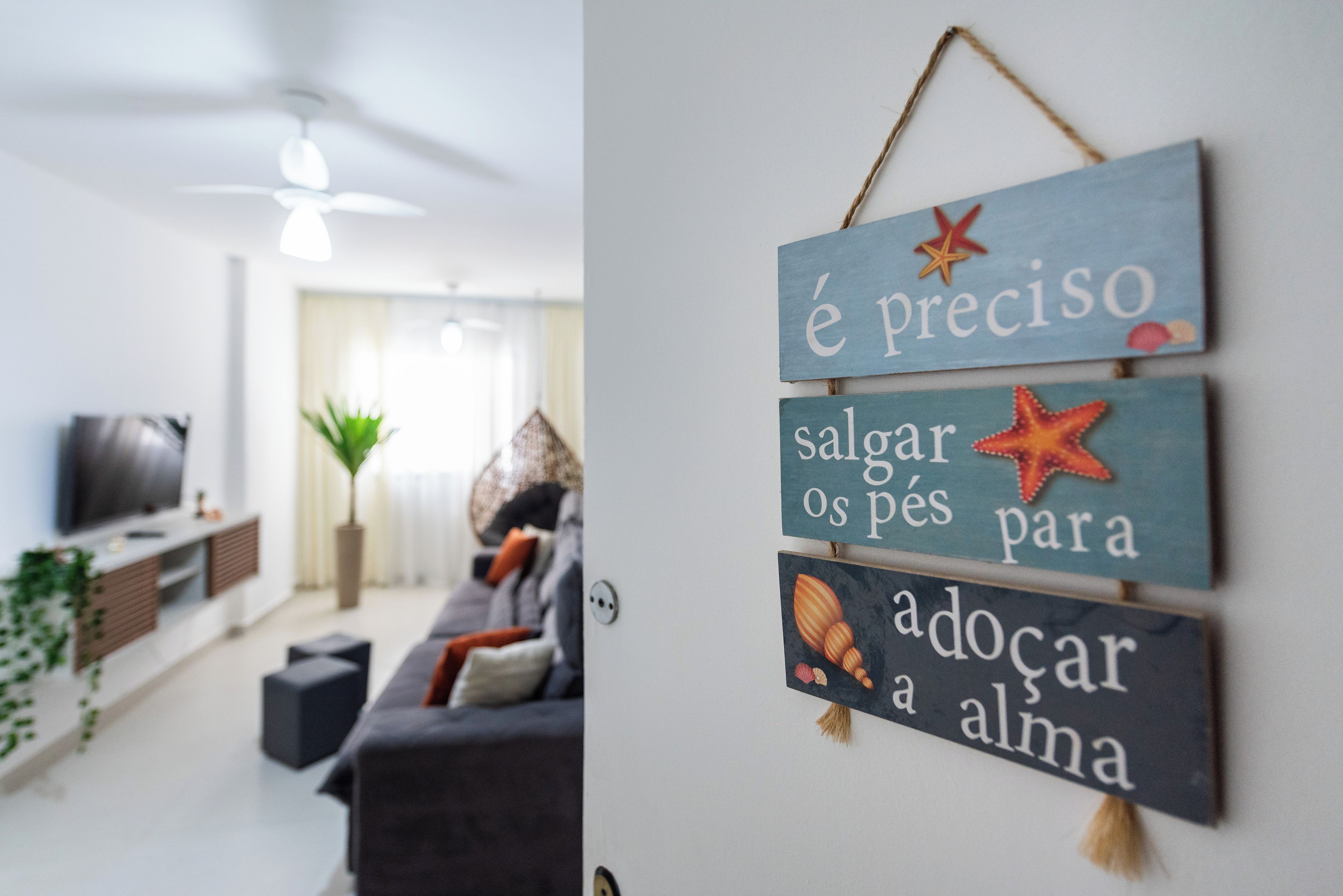 Uma sala de estar com sofá, televisão e uma parede decorada com placas.