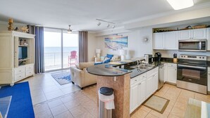 Uma cozinha moderna com ilha central, armários brancos e eletrodomésticos de aço inoxidável.