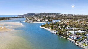An aerial view of a coastal area with a marina, beachfront properties, and a hill in the background. - Mariners Point 5 Noosaville (Noosaville)