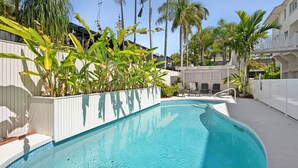 A swimming pool with a white deck, surrounded by palm trees and a white fence. - Mariners Point 5 Noosaville (Noosaville)