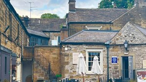 A stone building with outdoor seating, a staircase, and a sign for 'Castle Inn'.