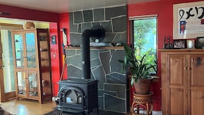 Ein gemütliches Wohnzimmer mit Kamin aus Stein, Holzschränken und einem Glastisch mit Papieren.