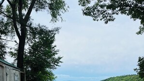 Eine Holzhütte mit Blick auf einen See und sanfte Hügel in der Ferne.