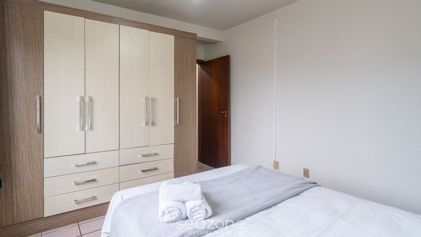 Un dormitorio con cama, armario y ventilador de techo.