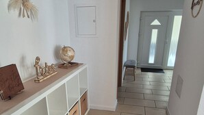 A hallway with a white wall, a wooden bench, a globe, and a welcome sign. - Vacation apartment AU (Bitburg)