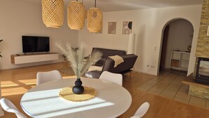 A modern living room with a dining area, a fireplace, and a TV. - Vacation apartment AU (Bitburg)