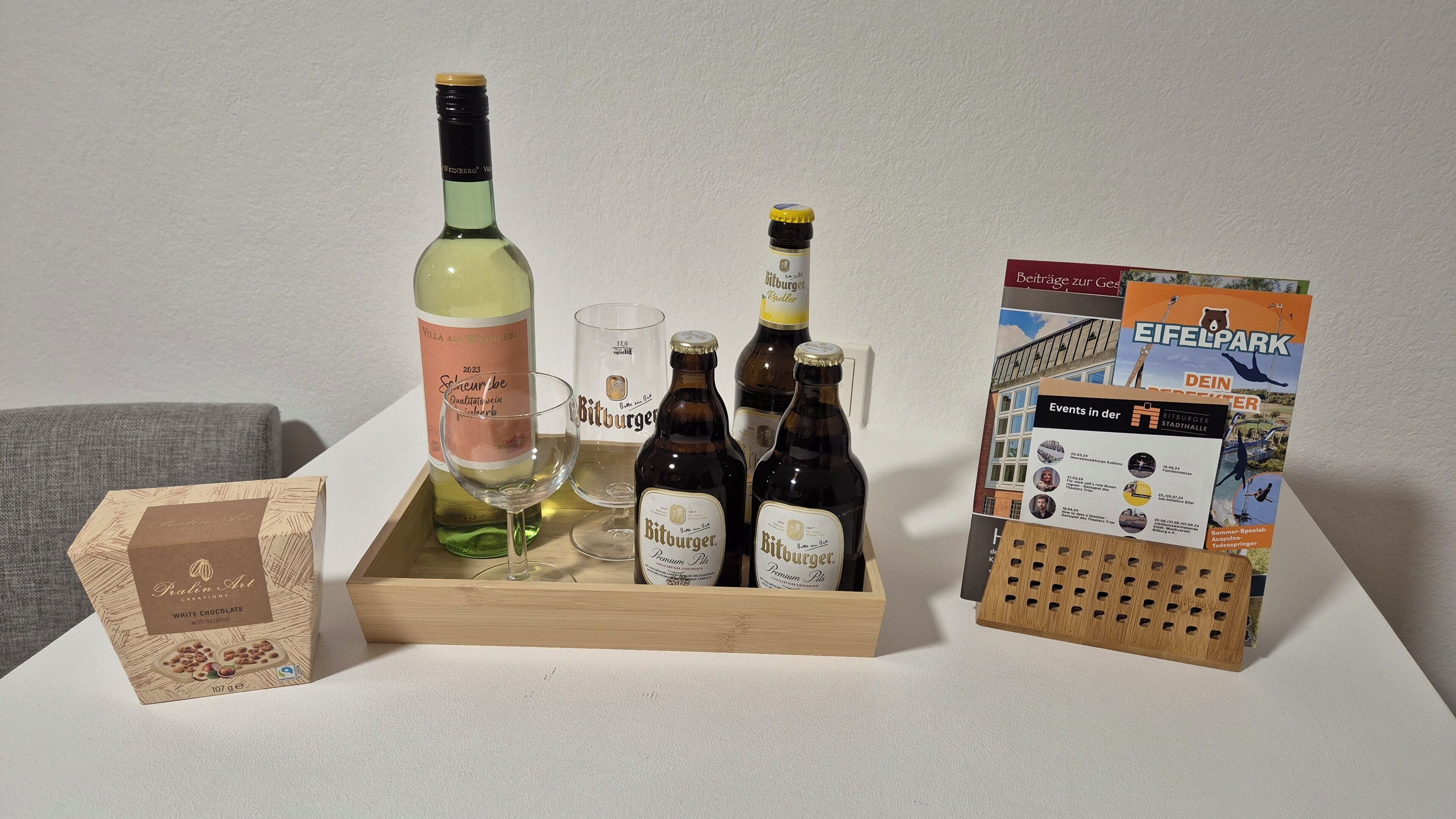 A wooden tray with bottles, glasses, and a brochure on a table.