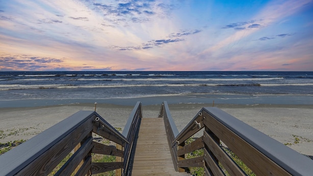 A wooden boardwalk leading to a beach with waves in the background. - Flip Flop Living North (New Smyrna Beach)