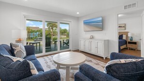 A modern living room with a sofa, armchairs, a round coffee table, and a view of the outdoors through large sliding glass doors.