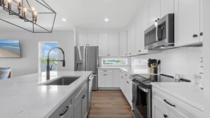 A modern kitchen with white cabinetry, stainless steel appliances, and a large island.