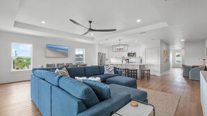A modern living room with a sectional sofa, a dining area, and a kitchen in the background.