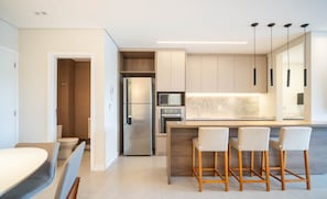 A modern kitchen with a central island, bar stools, and built-in appliances. - Apt With Balcony and Barbecue in Jurere Ihd0101 (Florianópolis)